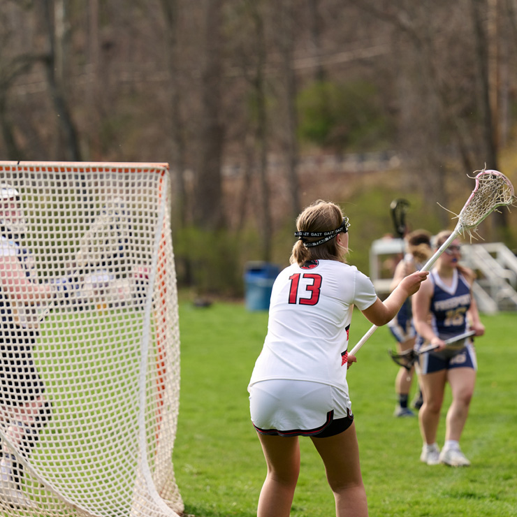 Teenage girls play senior school varsity lacrosse game